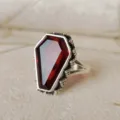 Primer plano del anillo gótico punk en forma de ataúd con gema roja y detalles plateados. - Talla 6 / Oro blanco