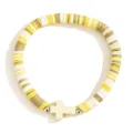 Gros plan du bracelet en perles d'argile colorées avec une croix élégante et un cordon élastique. - Beige