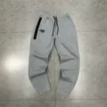 Detailed view of grey casual sweatpants featuring a black zipper pocket and custom embroidery. - M / Bottoms / Light Gray