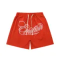 Detailed view of red waffle knit shorts featuring white cursive embroidery and drawstring waist. - S / Bottoms / Red