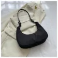 Détail élégant du petit sac à bandoulière hobo en nylon noir sur fond de veste crème. - Chaîne Double / Noir avec double chaîne