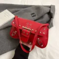Sac à bandoulière de moto en cuir rouge avec boucles métalliques et rivets pour les déplacements. - Rouge