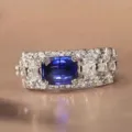 Detailed shot of wide pave diamond ring featuring emerald-cut blue sapphire with double prongs. - Size 6 / White Gold
