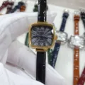 Gros plan détaillé du cadran de montre à quartz carré avec chiffres romains élégants. - Boîtier Or Cadran Noir Bracelet Noir