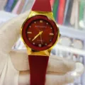 Gros plan détaillé d'une montre à quartz rouge avec lunette dorée et bracelet en silicone. - Rouge