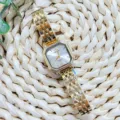 Detail shot of the gold quartz watch with octagonal dial and metallic link strap. - Gold White Dial