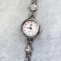 Nahaufnahme Detail der Damenuhr mit Quarzwerk, Kristall-Dreiecken und weißem Zifferblatt. - Silbernes Gehäuse Rosa Zifferblatt