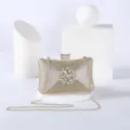 Gold glitter evening clutch bag detail with rhinestone flower clasp and gold chain strap. - Gold