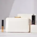 Elegant white evening clutch bag with glossy textured surface and gold metal clasp detail. - White
