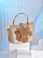 Gold evening clutch bag detail showcasing rhinestone flower decoration and metal handle clasp. - Gold