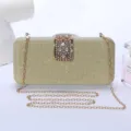 Elegante bolso de noche tipo clutch dorado con purpurina, cierre de estrás y cadena fina. - Dorado