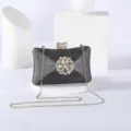 Detailed shot of sparkling black evening clutch with rhinestone floral clasp and gold chain. - Dark Gray