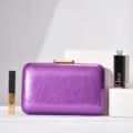 Purple glossy textured evening clutch bag with gold metallic clasp detail for party wear. - Violet