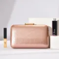 Detailed view of a rose gold evening clutch bag with textured surface and elegant metallic clasp. - Champagne