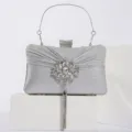 Détail de pochette de soirée argentée avec broche florale strassée et pendentif gland. - Argent