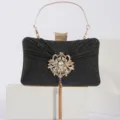 Élégante pochette de soirée noire pailletée, poignée dorée et broche florale en strass. - Noir