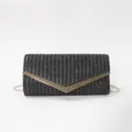 Elegant black woven envelope clutch detail with stylish gold V-shaped metal clasp and chain. - Black