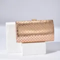 Rose gold textured evening clutch bag with metallic clasp and polka dot laser design. - Rose Gold