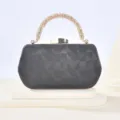Detail of black textured evening clutch featuring rhinestone handle and a gold clasp. - Black