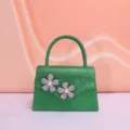 Green sparkly evening bag detail showcasing the exquisite rhinestone pearl flower decoration. - Green