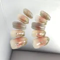 Close-up detail of short press-on nails with gradient nude pink, gold foil, and sparkling rhinestones. - XH-085 Style
