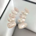 Primer plano detallado de uñas postizas rosa nude con diseño floral 3D y estrellas brillantes. - M Ovalado Corto / Estilo 087