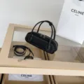 Black leather cylindrical shoulder bag with white stitching and versatile strap. - 26x7x9cm / Black