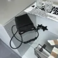 Chic mini black leather phone bag for women featuring a stylish star charm and woven strap. - Black