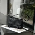 Black leather messenger bag detail, minimal vintage shoulder bag showcase in urban scene. - 23*7*17cm / Black