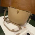 Minimalist PU leather saddle bag with metallic push-lock closure and adjustable strap. - Apricot