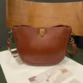 Detail view of brown leather saddle bag showcasing premium texture and metal lock. - Brown