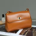 Detailed view of a vintage brown leather shoulder bag with metallic lock closure and strap. - 24*18*18cm / Sunset Yellow