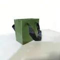 Grüne Papiertragetasche mit schwarzen Schleifengriffen, ideal für Schmuckverpackung und Geschenke. - Geschenktüte