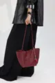 Detailed view of the burgundy genuine leather bucket tote bag with cute strawberry charm. - Red