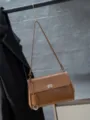 Close-up detail of retro brown genuine leather shoulder bag with chic metal lock and elegant charm. - Gold Brown