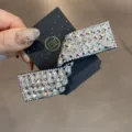Détail de pince à cheveux en strass avec design en cristal étincelant et carte de présentation. - Blanc