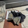 Gros plan détaillé d'un chouchou à nœud en strass étincelant avec un tissu en satin noir. - Blanc