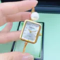 Detailansicht der goldenen Armbanduhr mit Perle und schickem quadratischen Zifferblatt. - Quadrat-Alles Gold Weißes Zifferblatt