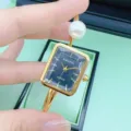 Nahaufnahme einer luxuriösen goldenen Armbanduhr mit schwarzem Zifferblatt und Perle. - Quadrat-Alles Gold Schwarzes Zifferblatt