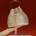 Golden glitter bucket bag with metal round handle and elegant evening chain tassel design. - Gold