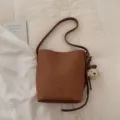 Retro large capacity bucket bag for women, stylish leather shoulder bag for daily commute and casual use. - Yellowish Brown With Pendant