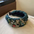 Detailaufnahme des dunkelgrünen, geflochtenen Strass-Haarreifs mit funkelnden Kristallblumen. - Grün