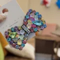 Vue détaillée d'une pince à cheveux nœud en strass colorés avec carte de présentation. - Multicolore Clair