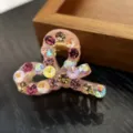 Detailed view of small hair claw clip with sparkling colorful rhinestones for elegant styling. - Pink