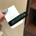 Gros plan détaillé de la pince à cheveux strass vert velours sur carte de support. - Vert