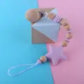 Close-up of wooden and silicone baby pacifier clip with star teether and beads detail. - Purple