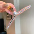 Vue de detail d'une pince a cheveux en acrylique rose avec strass et perle pour coiffure. - Rose