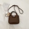 Brown PU leather commuter shoulder bag with cute bear pendant and metal lock design. - Brown with Pendant