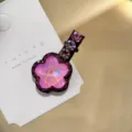 Gros plan d'une pince à cheveux fleur en cristal rose scintillant sur une carte blanche. - Rose
