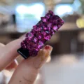 Gros plan détaillé d'une superbe petite pince à cheveux ornée de strass magenta étincelants. - Rose rouge